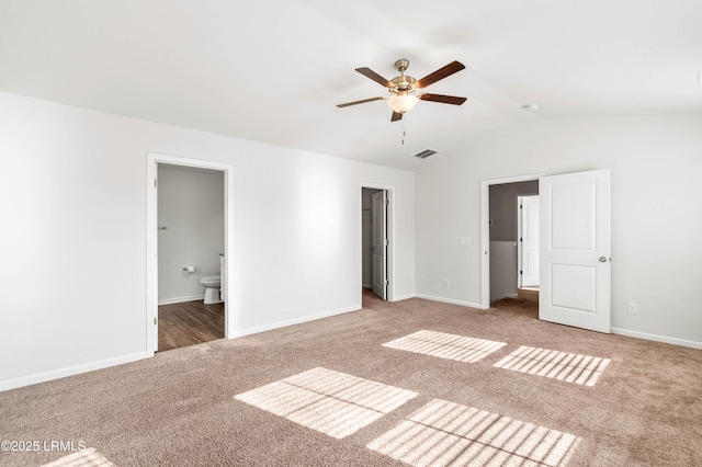 unfurnished bedroom with carpet floors, lofted ceiling, visible vents, ensuite bathroom, and baseboards