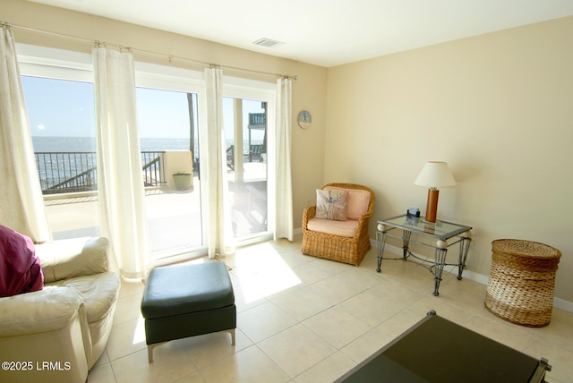 living area with a water view, tile patterned flooring, baseboards, and visible vents