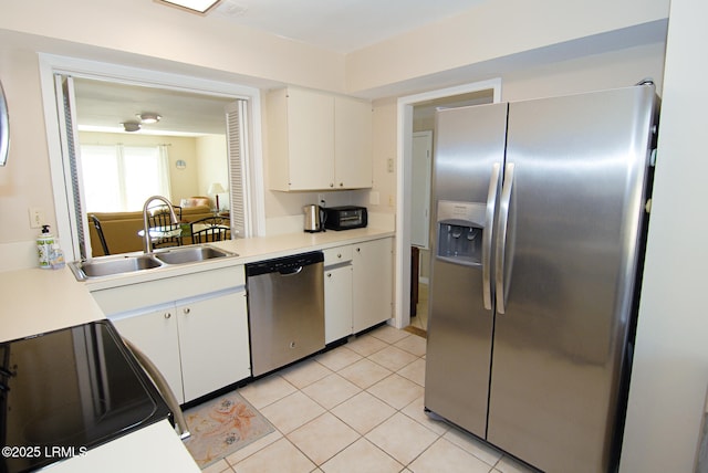 kitchen with a sink, light countertops, light tile patterned flooring, stainless steel appliances, and white cabinetry