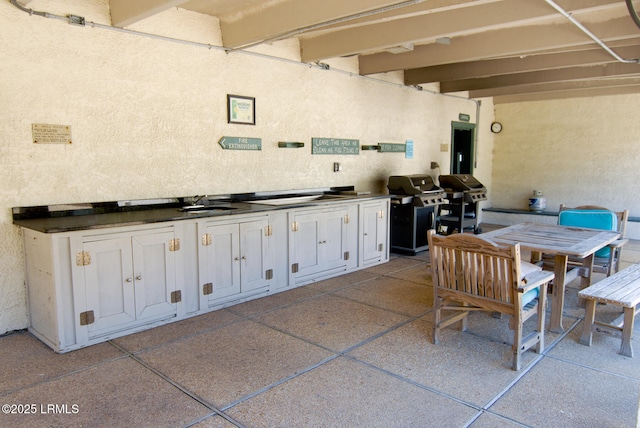 view of patio / terrace with outdoor dining space, a sink, grilling area, and an outdoor kitchen