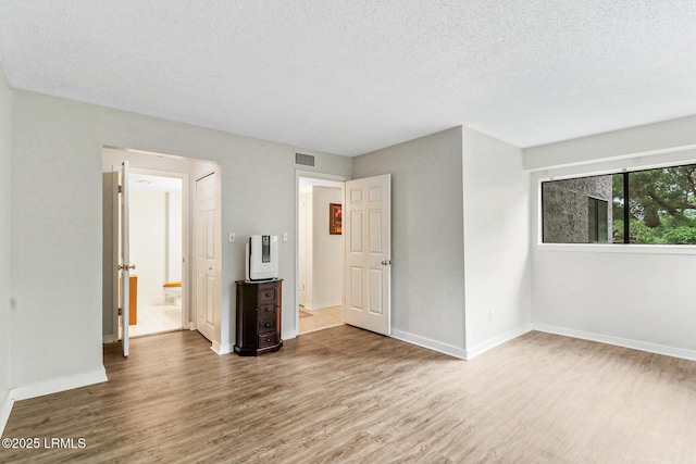 70 Paddle Boat Ln Unit 207, Hilton Head Island, SC 29928 - unfurnished bedroom featuring wood finished floors, a textured ceiling, and ensuite bath