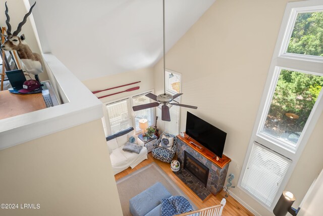 living room with hardwood / wood-style floors, a fireplace, ceiling fan, and a high ceiling