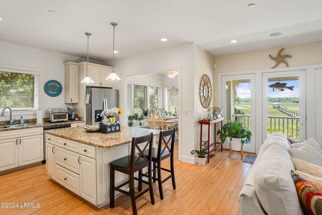 kitchen with a kitchen island, pendant lighting, sink, stainless steel refrigerator with ice dispenser, and light hardwood / wood-style flooring