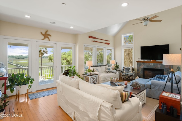 living room with ceiling fan, lofted ceiling, a fireplace, and light hardwood / wood-style flooring