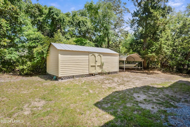 view of outdoor structure with a carport and a lawn