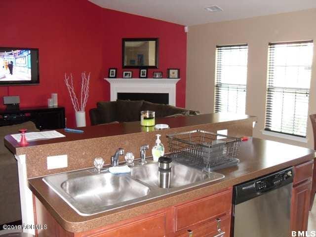 kitchen featuring a sink, stainless steel dishwasher, brown cabinetry, and open floor plan