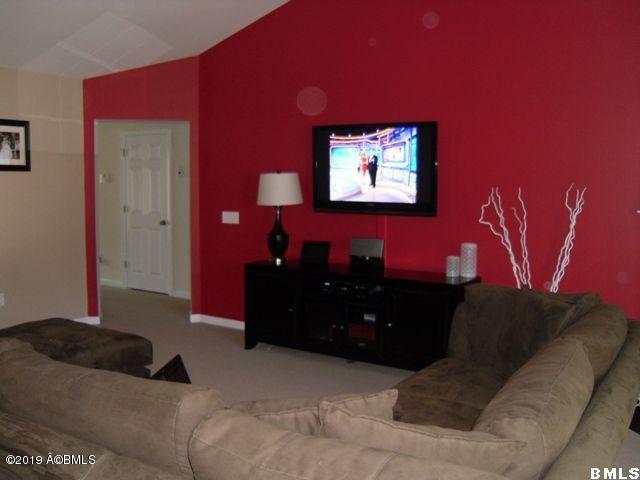 carpeted living room featuring baseboards and vaulted ceiling