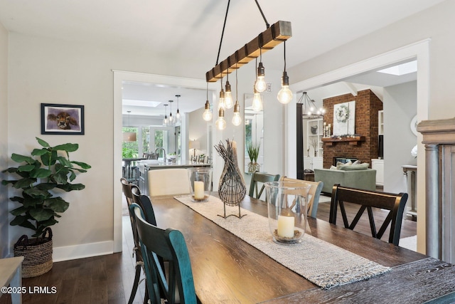 30 Longwood Dr, Okatie, SC 29909 - dining space featuring a chandelier, a brick fireplace, dark wood-style flooring, and baseboards