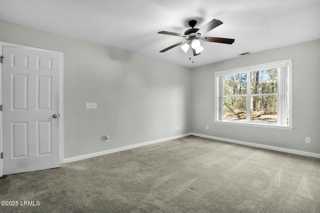 carpeted empty room featuring a textured ceiling, ceiling fan, visible vents, and baseboards