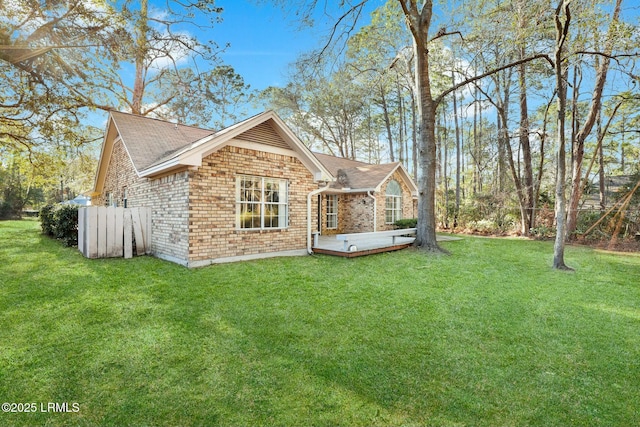 rear view of property with a yard, a wooden deck, and brick siding