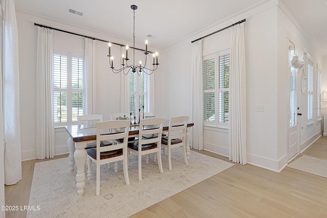 dining space featuring visible vents, ornamental molding, light wood-style floors, baseboards, and a notable chandelier