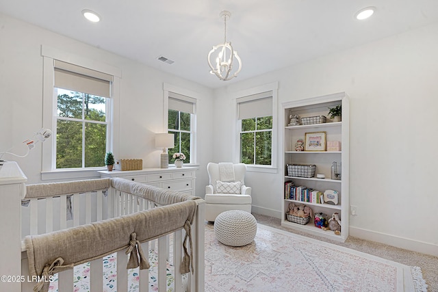 carpeted bedroom with visible vents, baseboards, recessed lighting, a nursery area, and a chandelier