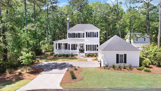 colonial house with roof with shingles, covered porch, driveway, and a front yard