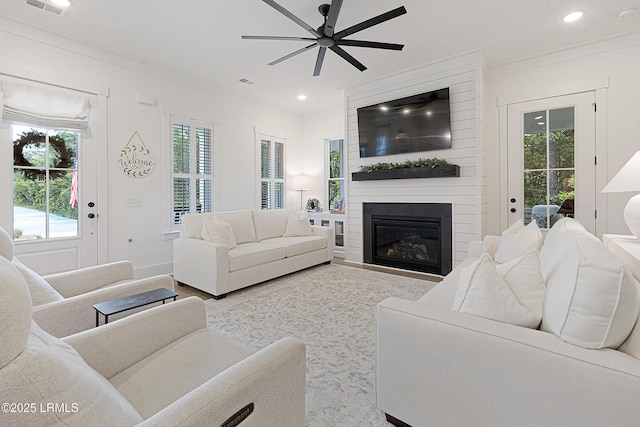 living room featuring a large fireplace, ceiling fan, recessed lighting, and ornamental molding