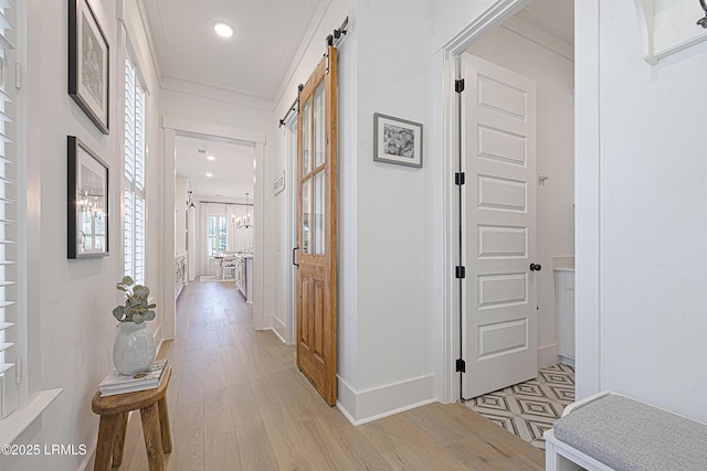 corridor with crown molding, a barn door, baseboards, light wood-style floors, and recessed lighting