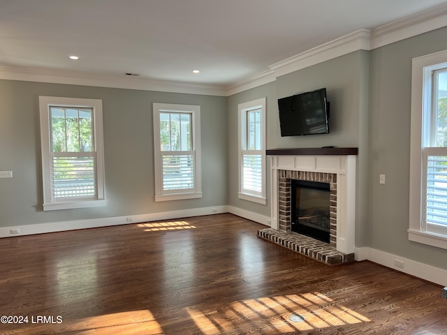 unfurnished living room featuring crown molding, plenty of natural light, dark hardwood / wood-style floors, and a brick fireplace