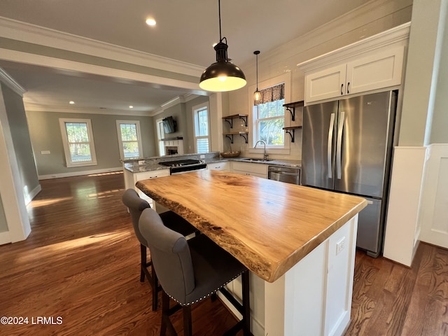 kitchen with white cabinetry, crown molding, decorative light fixtures, a kitchen island, and stainless steel appliances