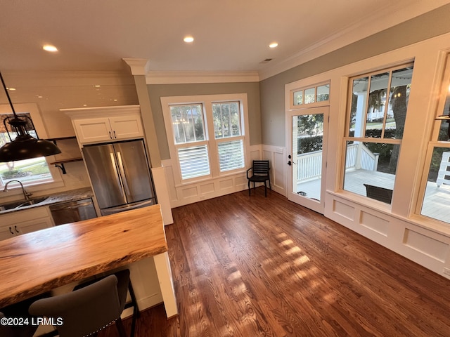 kitchen featuring butcher block countertops, crown molding, appliances with stainless steel finishes, white cabinetry, and dark hardwood / wood-style flooring