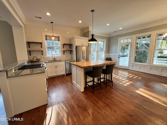 kitchen with sink, white cabinets, pendant lighting, stainless steel appliances, and backsplash