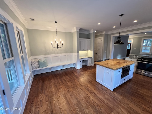 kitchen with butcher block counters, a kitchen island, pendant lighting, stainless steel appliances, and white cabinets