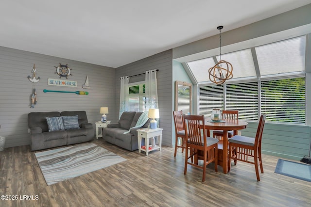 dining area featuring an inviting chandelier, hardwood / wood-style flooring, a wealth of natural light, and wooden walls