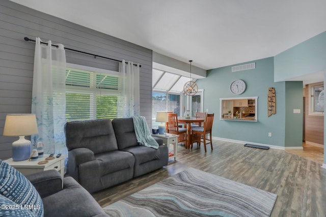 living room with a notable chandelier, hardwood / wood-style floors, and wood walls