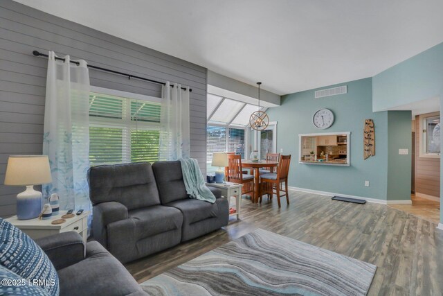 living room with a notable chandelier, hardwood / wood-style floors, and wood walls