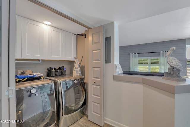 laundry area with light hardwood / wood-style flooring, washer and clothes dryer, and cabinets