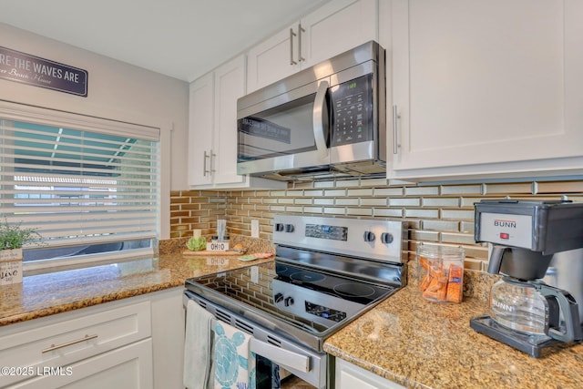 kitchen with backsplash, light stone countertops, white cabinets, and appliances with stainless steel finishes