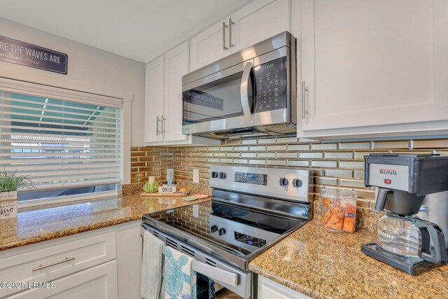 kitchen with backsplash, light stone countertops, white cabinets, and appliances with stainless steel finishes