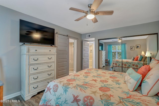 bedroom with ensuite bathroom, ceiling fan, light hardwood / wood-style floors, a barn door, and a closet