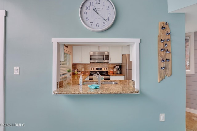 kitchen featuring sink, appliances with stainless steel finishes, white cabinets, light stone countertops, and backsplash