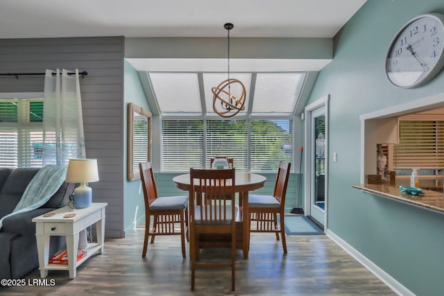 dining room featuring dark wood-type flooring, vaulted ceiling, and a notable chandelier