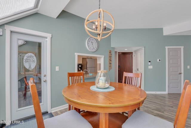 dining space with an inviting chandelier, vaulted ceiling, and light wood-type flooring