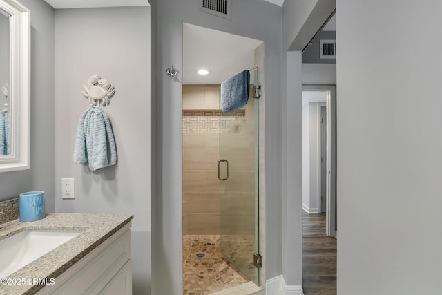 bathroom featuring walk in shower, vanity, and hardwood / wood-style flooring