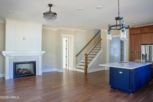 kitchen with pendant lighting, ornamental molding, a kitchen island, and stainless steel refrigerator with ice dispenser