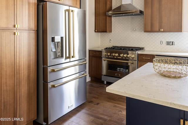 kitchen featuring tasteful backsplash, dark wood-type flooring, wall chimney range hood, and premium appliances