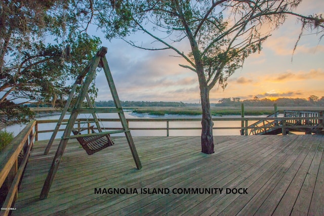 deck at dusk with a water view and a boat dock