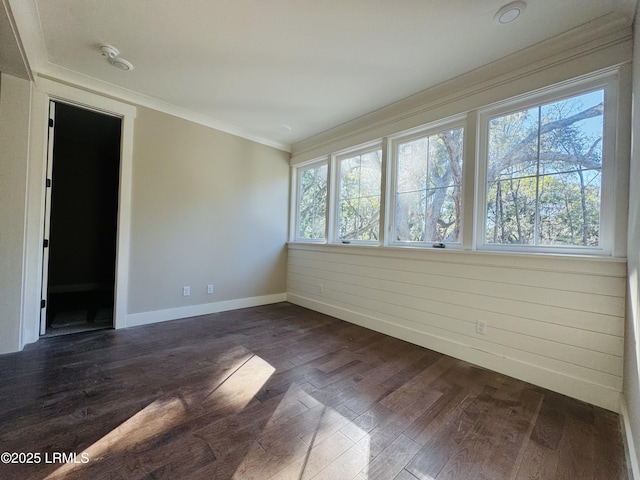 empty room with ornamental molding and dark hardwood / wood-style floors