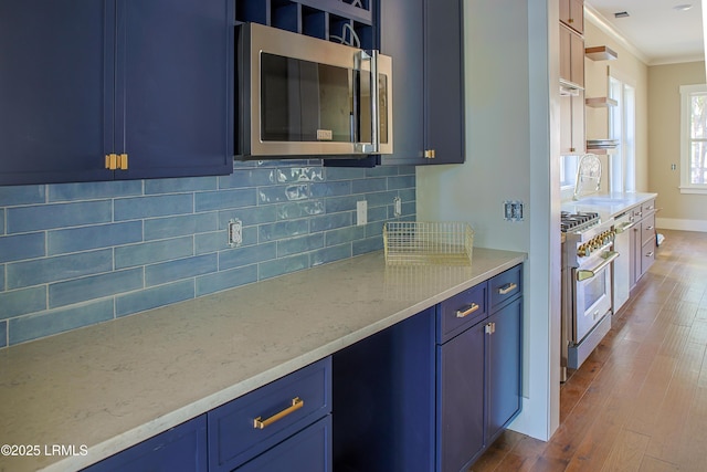 kitchen featuring blue cabinets, crown molding, appliances with stainless steel finishes, and dark hardwood / wood-style floors