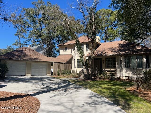 view of front of property with driveway, a chimney, an attached garage, a front lawn, and stucco siding