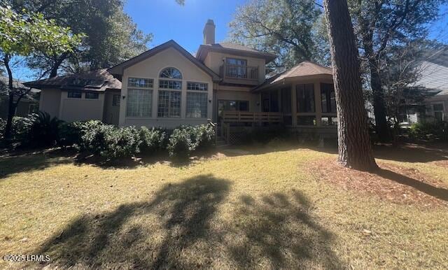 back of house with a yard and a balcony