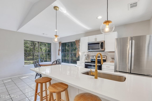 kitchen featuring a breakfast bar, tasteful backsplash, white cabinetry, hanging light fixtures, and stainless steel appliances