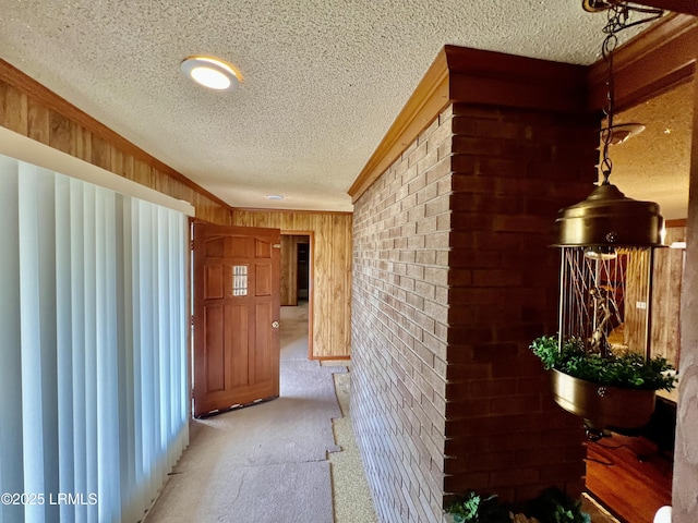 hall with crown molding, carpet floors, a textured ceiling, and wood walls