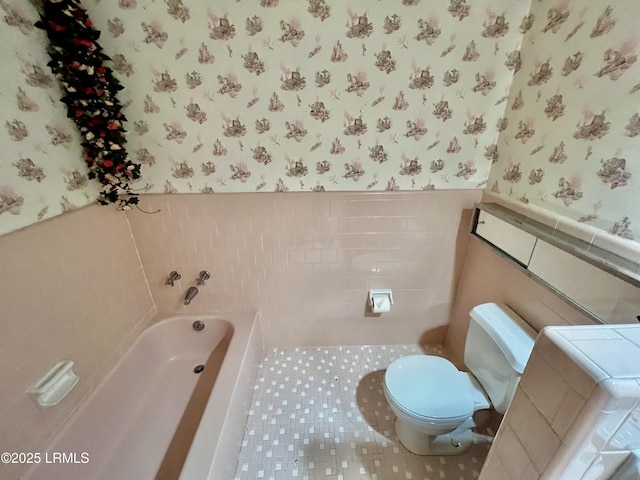 bathroom featuring tile walls, washer / clothes dryer, tile patterned floors, toilet, and a bathing tub