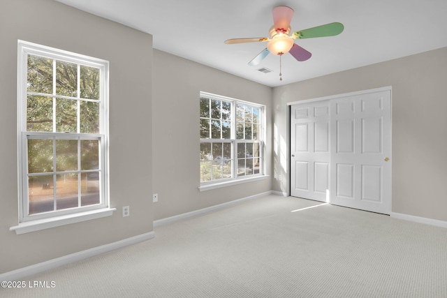 unfurnished bedroom with ceiling fan, light colored carpet, and a closet