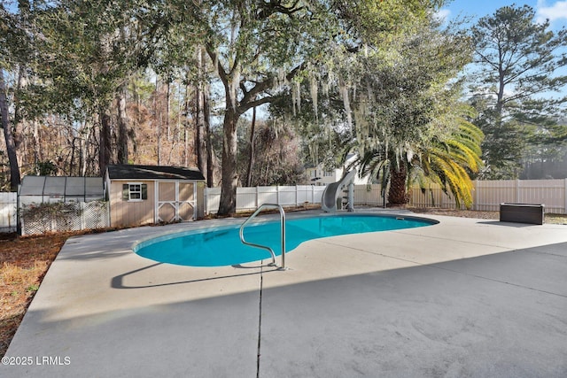 view of pool with a patio area, a storage unit, and a water slide