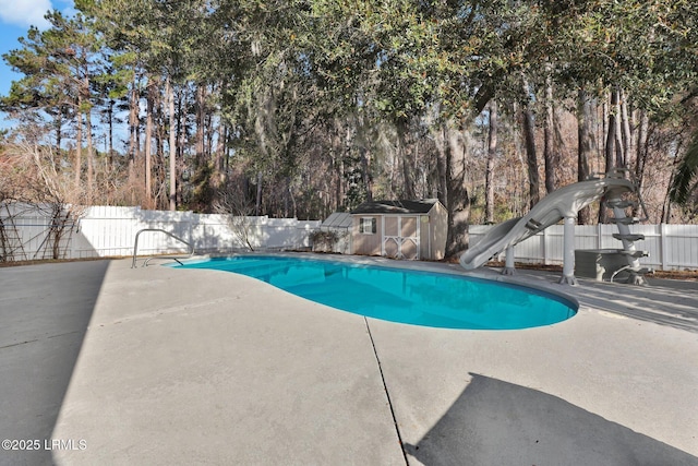 view of swimming pool with a shed, a patio area, and a water slide