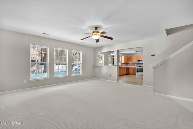 unfurnished living room featuring light colored carpet and ceiling fan