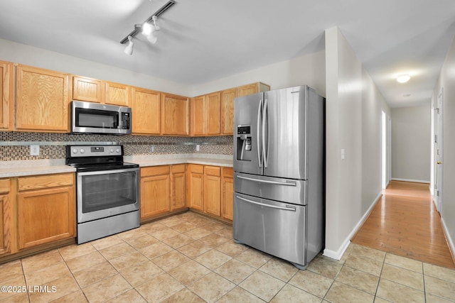 kitchen with tasteful backsplash, light tile patterned floors, and stainless steel appliances